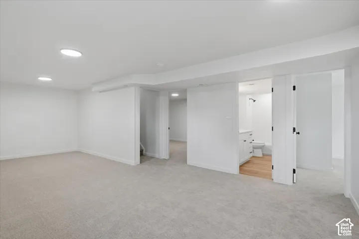 Neutral-toned carpeting, recessed ceiling lighting, and crisp white wall finishes