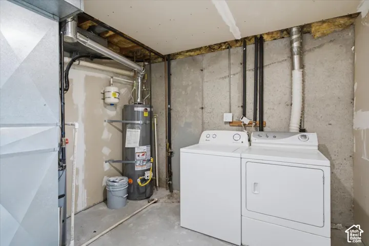 Utility area featuring a gas water heater, forced-air furnace unit, and dedicated laundry hookups with concrete foundation walls