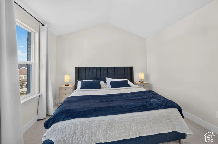 Vaulted ceiling, large window, neutral wall paint, light-toned flooring, and contemporary light fixtures