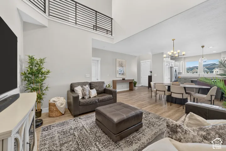 Open-concept living area featuring a two-story ceiling, wood-finish flooring, and a modern metal railing