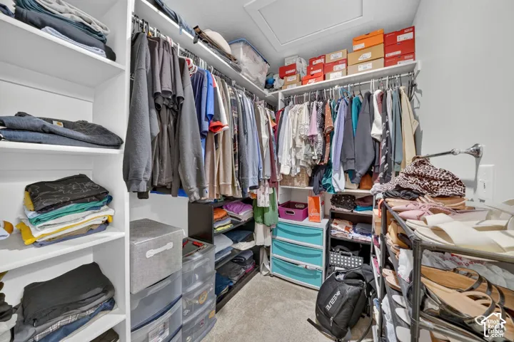 Walk-in closet featuring built-in shelving, multiple hanging rods, and an overhead access panel