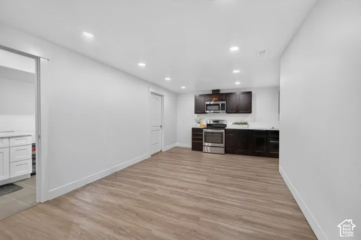 Wood-finish flooring, recessed lighting, dark wood cabinetry, stainless steel appliances, and white countertops