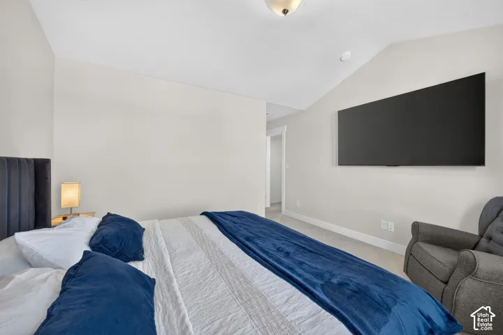 Vaulted ceiling, wall-mounted television, neutral wall color, recessed lighting, and carpeted flooring