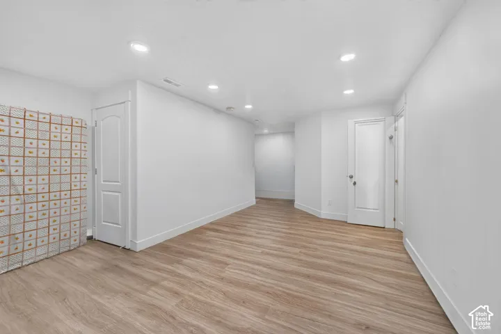 Recessed ceiling lighting, light wood-finish flooring, and white interior doors