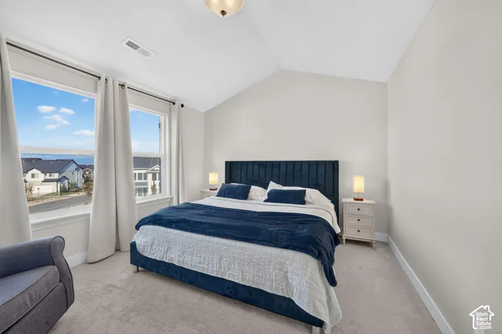Vaulted ceiling with a flush-mount light fixture, expansive windows, light-toned wall finish, and carpet flooring