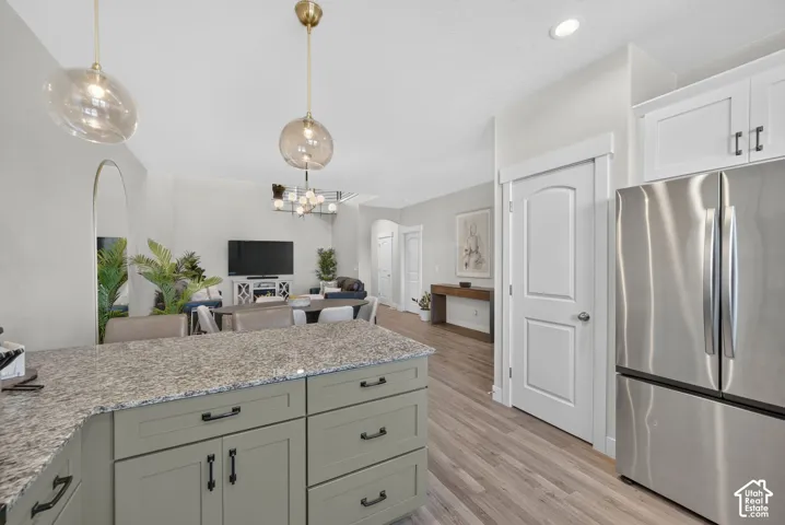 Kitchen island with stone-finish countertop, recessed lighting, and wood-finish flooring