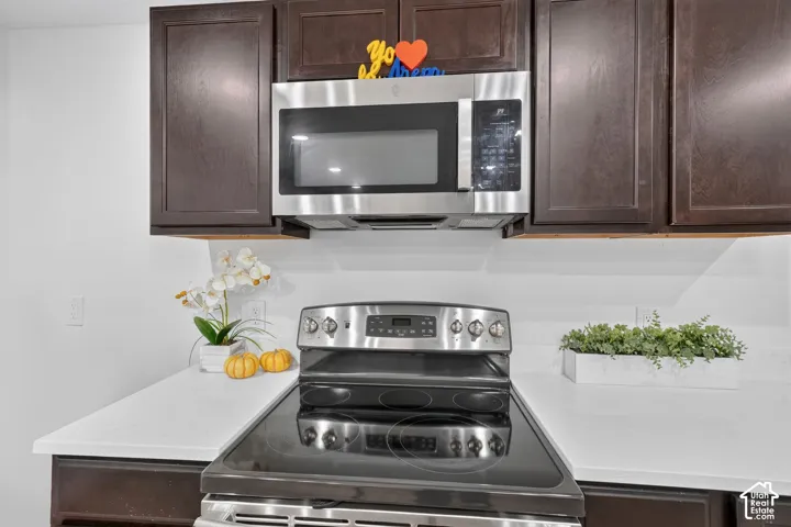 Stainless steel microwave and range, dark wood-finish cabinetry, and light-toned countertops