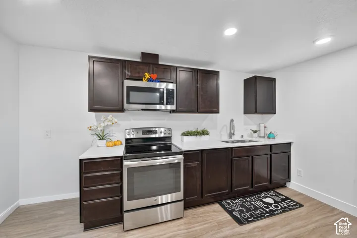 Kitchen featuring dark wood-finish cabinetry, white countertops, a stainless steel range, and a stainless steel microwave
