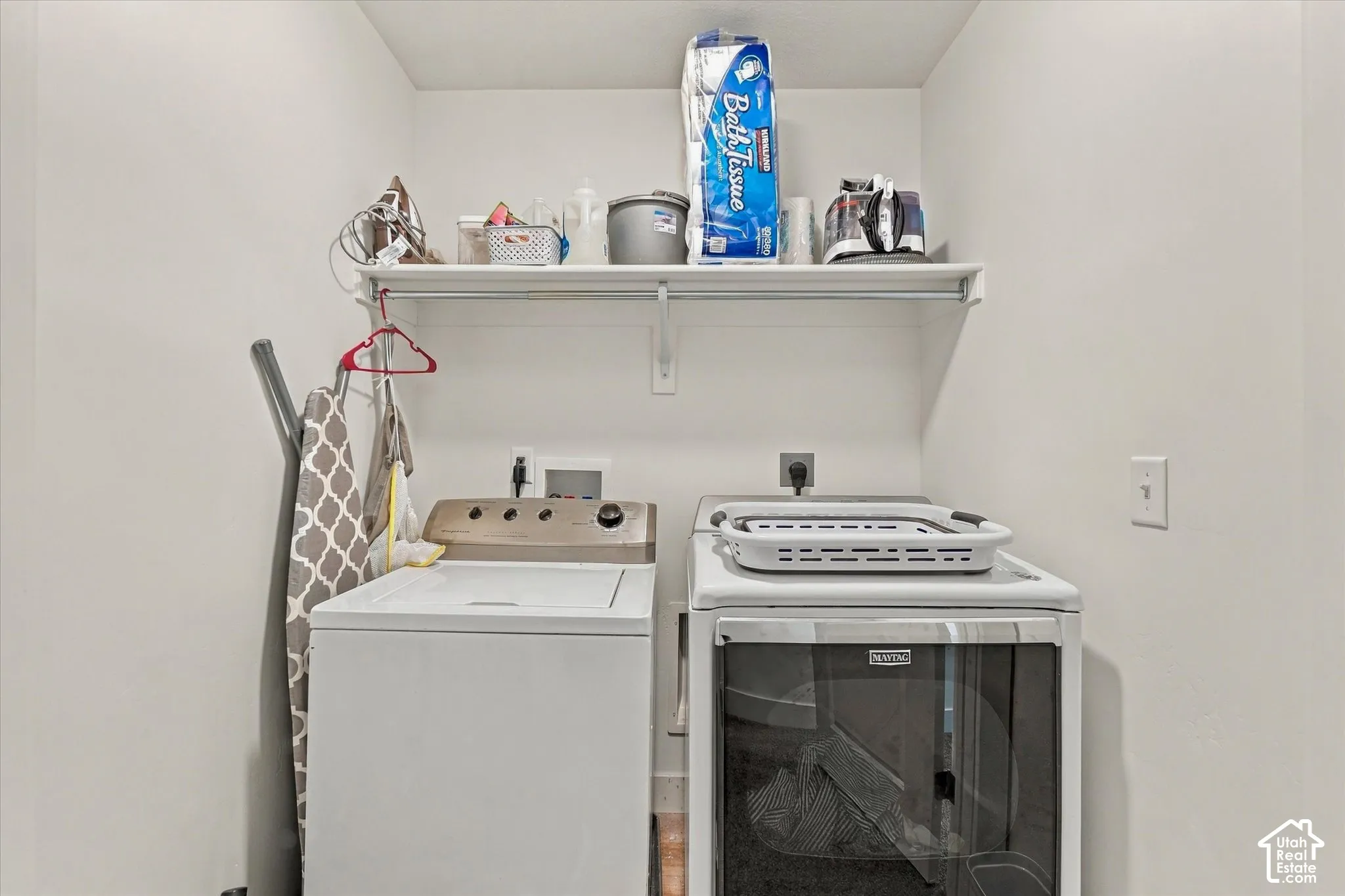 Utility area featuring a fixed overhead shelving unit with an integrated hanging rod