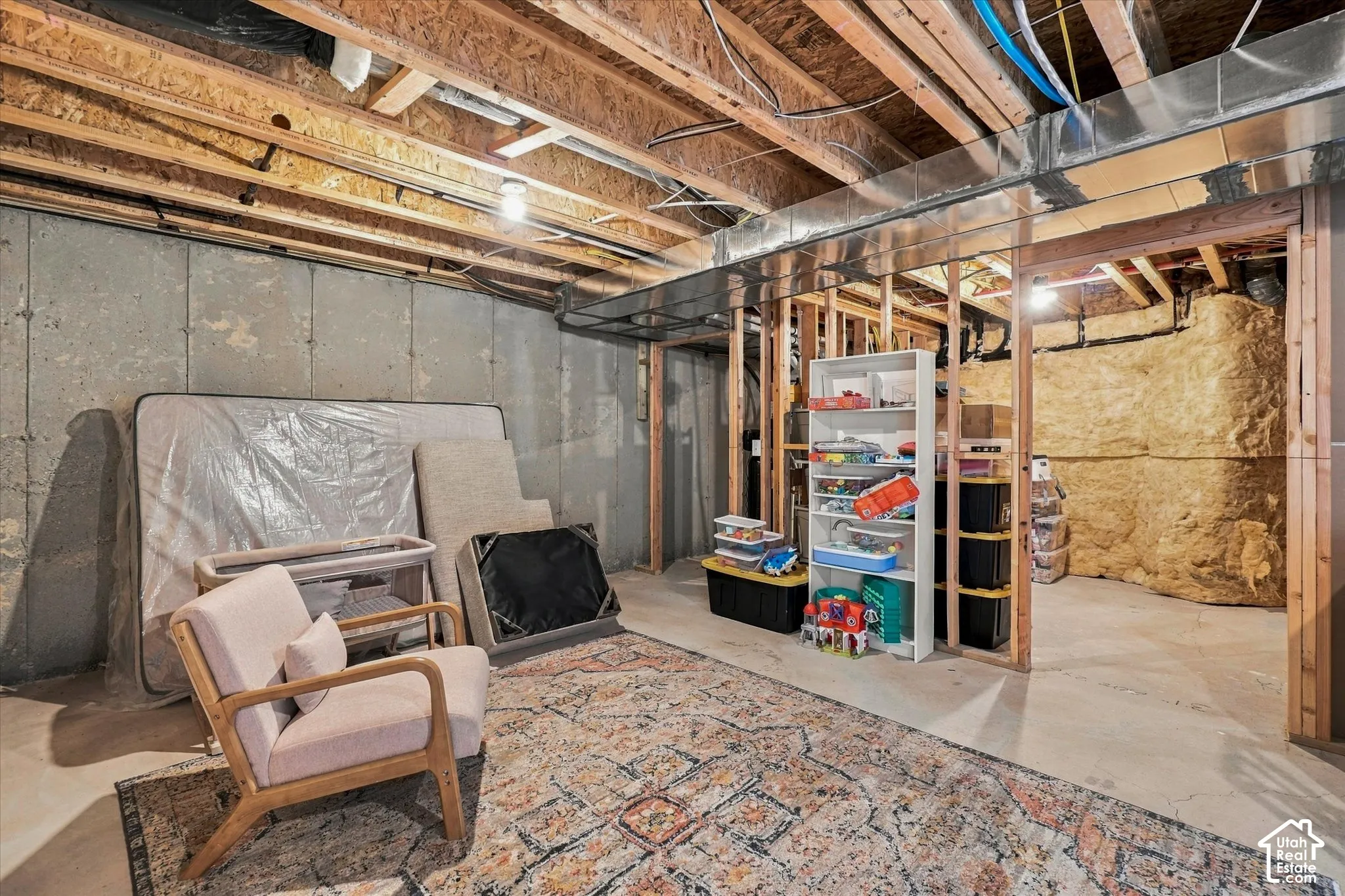 Unfinished utility space featuring exposed wood-framed joists, poured concrete foundation walls, and metal ductwork