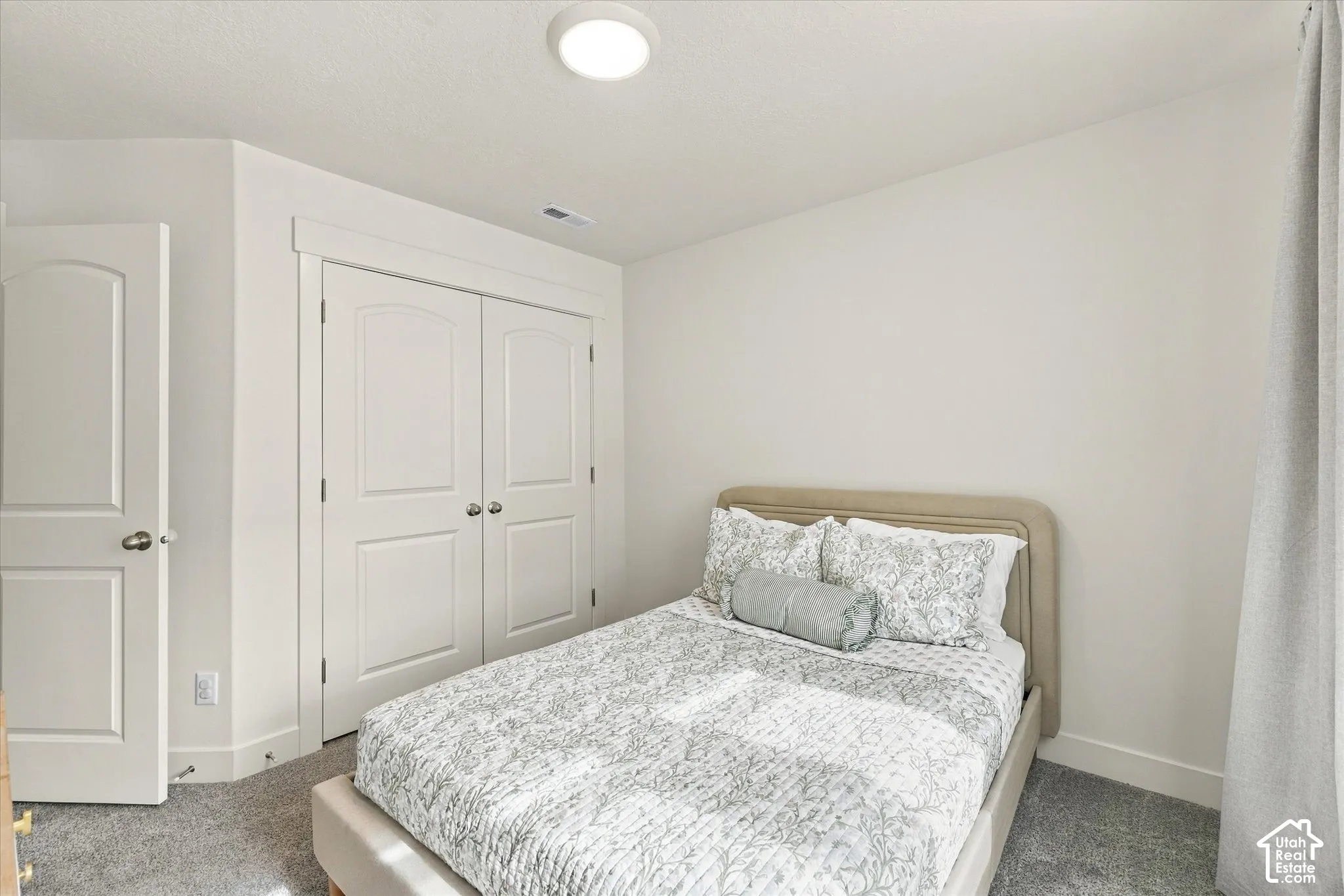 Bedroom featuring neutral-toned carpeting, double-door reach-in closet with paneling, and flush-mount overhead lighting