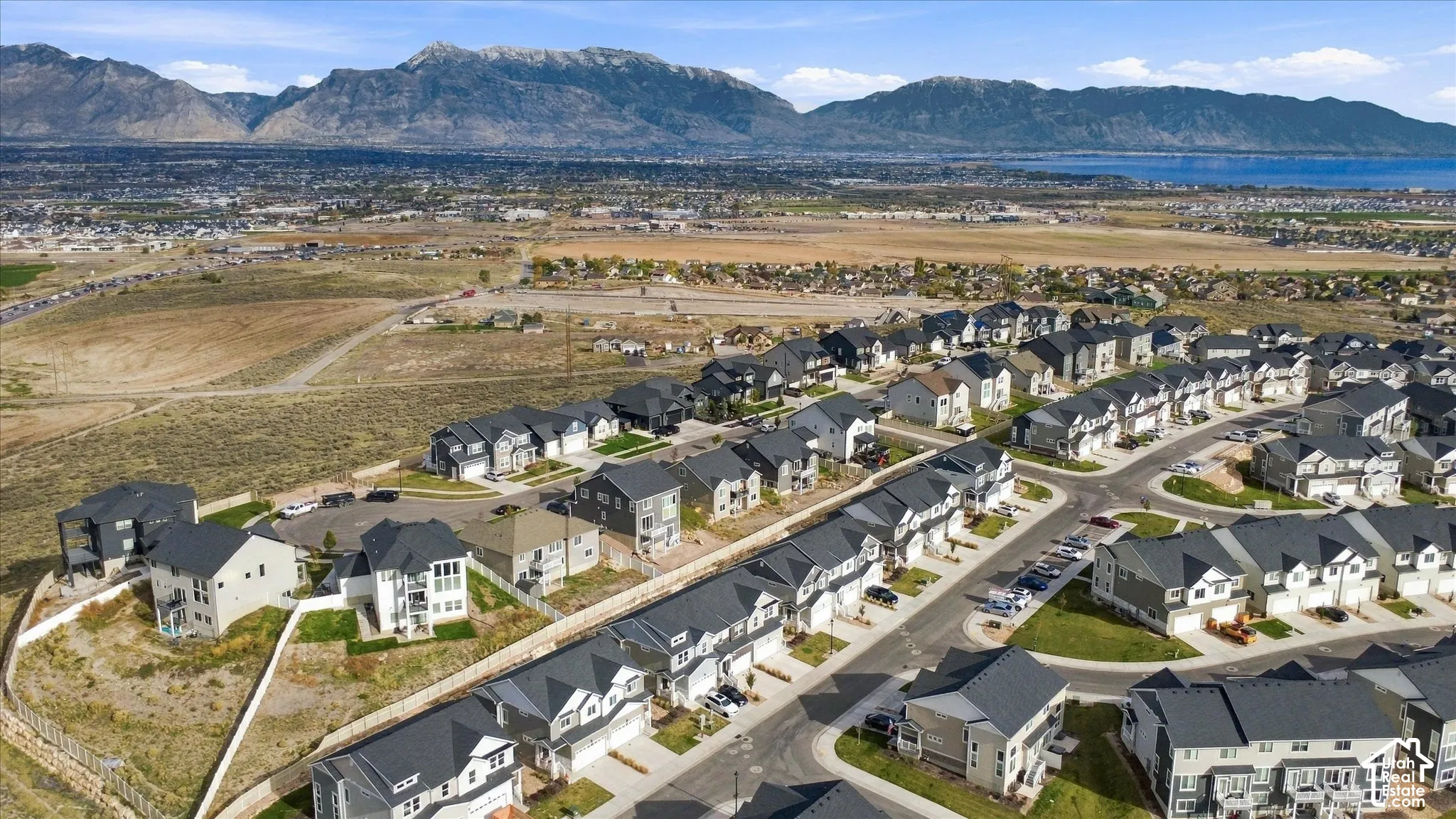 Aerial perspective featuring multi-story residential architecture with dark-toned shingle roofing, integrated garages, and mountainous landscape backdrop