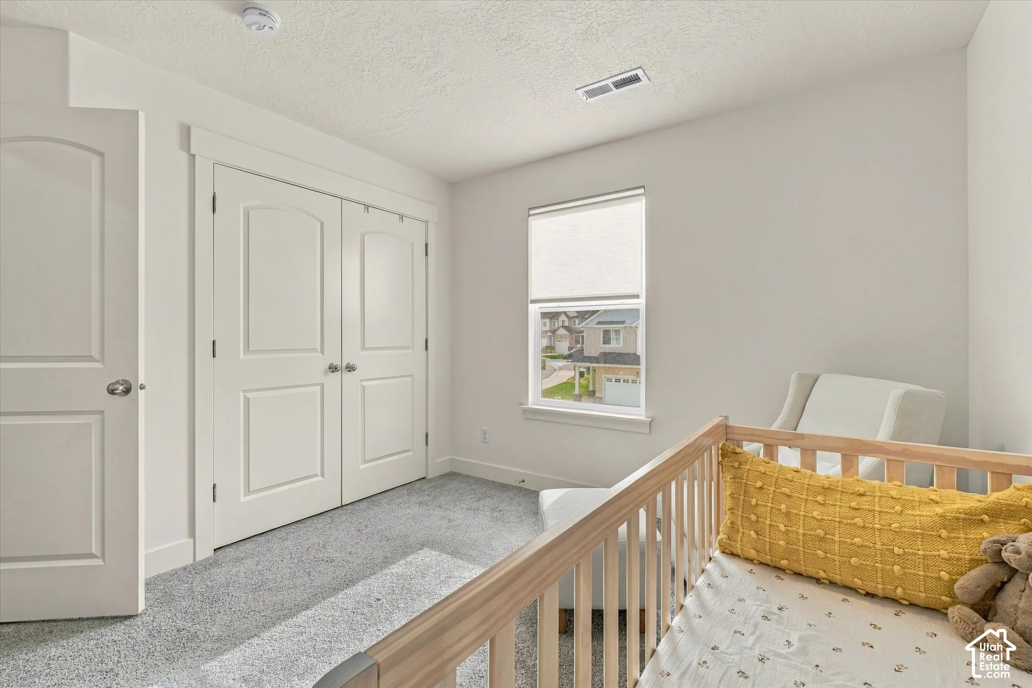 Neutral-toned carpeted flooring, double-panel interior door, dual-door reach-in closet, and window with integrated roller shade