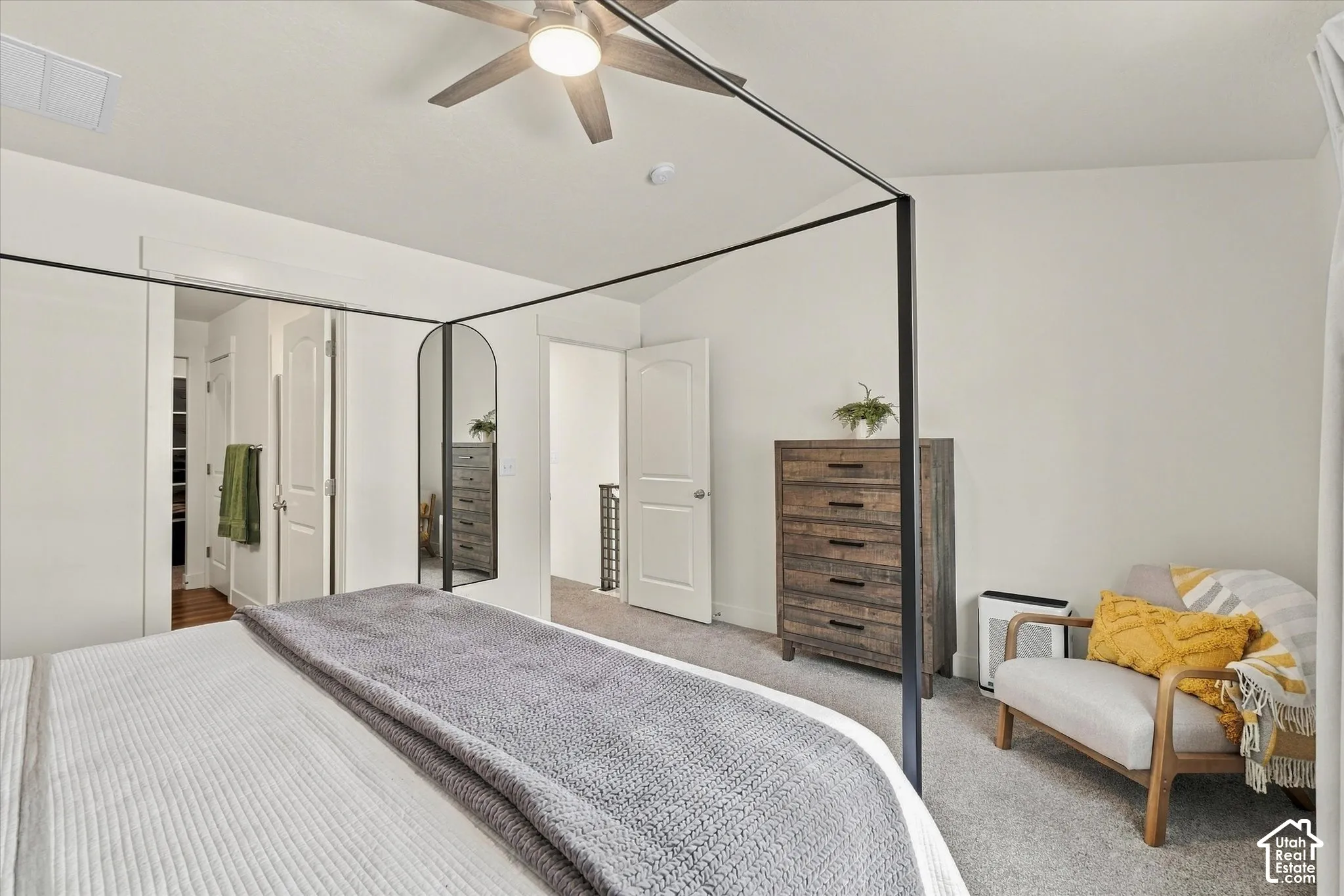 Vaulted ceiling featuring a central multi-blade ceiling fan with integrated lighting and neutral carpeting