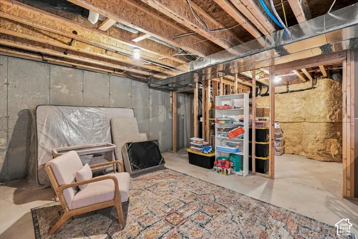 Unfinished utility space featuring exposed wood-framed joists, poured concrete foundation walls, and metal ductwork