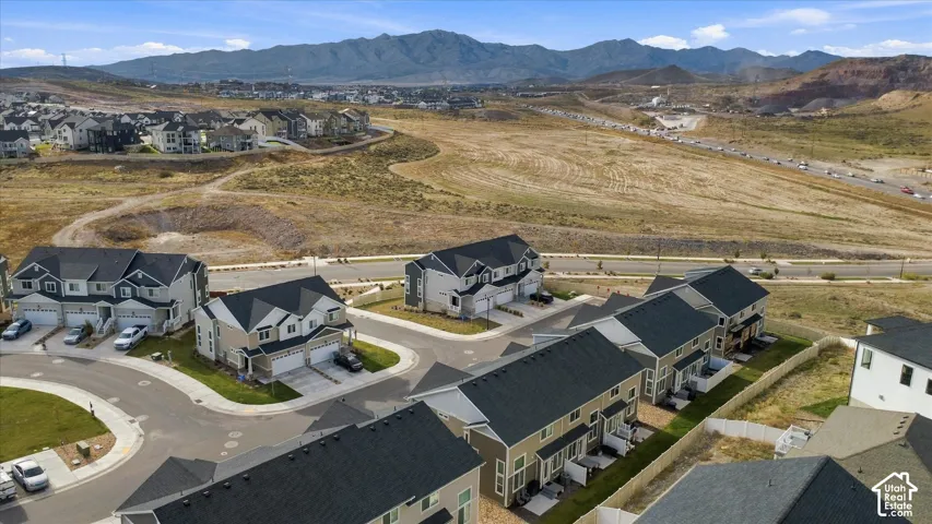 Aerial perspective of multi-family residences featuring multi-pitched roofs, attached garages, and a mountain range backdrop