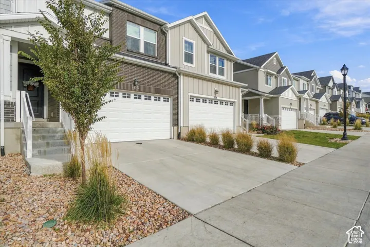 Multi-level exterior featuring a combination of brick and vertical board-and-batten siding, concrete driveway, attached multi-car garage, and landscaped rock garden beds