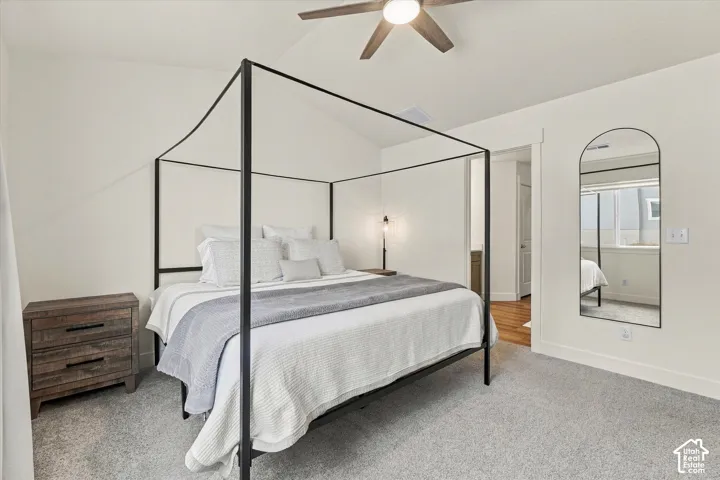 Bedroom featuring a vaulted ceiling, neutral wall coloring, carpeting, and a ceiling fan with integrated lighting