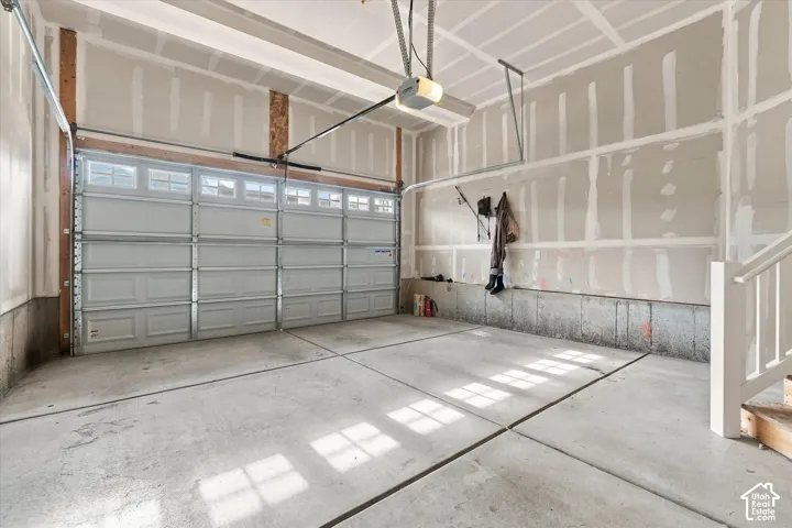 Multi-car garage featuring a sectional overhead door, concrete flooring, and an automated garage door opener