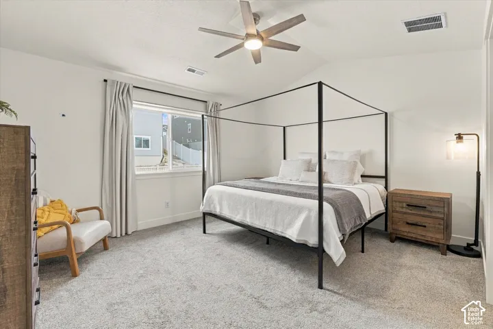 Neutral carpeting, vaulted ceiling, and overhead ceiling fan with integrated lighting