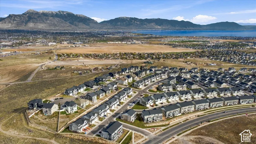 Aerial perspective of a multi-unit residential community featuring pitched rooflines, paved streets, and a mountainous backdrop