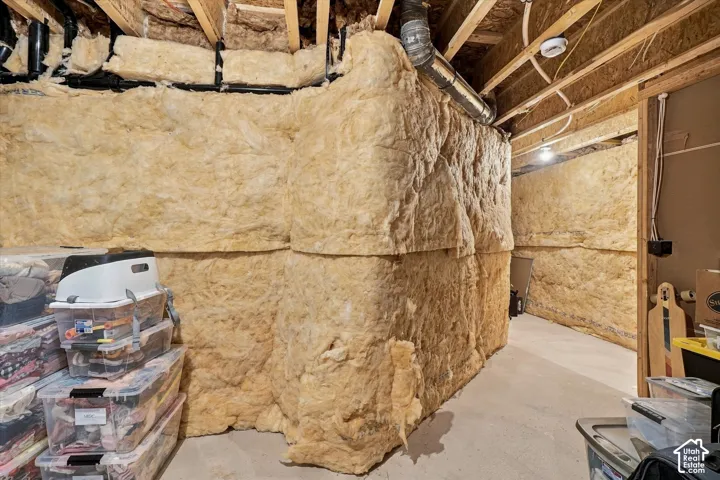 Unfinished lower level space featuring concrete flooring, exposed joists, and fiberglass batt insulation along foundation walls