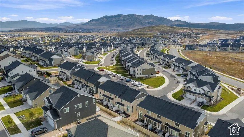 Aerial perspective of a suburban neighborhood featuring paved streets, multi-story residences with shingled roofs, and expansive mountain range backdrop