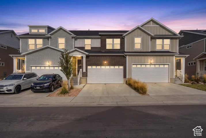 Multi-unit exterior featuring brick and board-and-batten siding, shingled gable roofs, and multiple attached garage bays