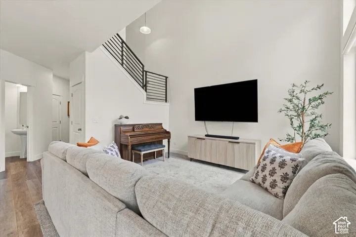 High-ceiling living area featuring wood-finish flooring and a staircase with a horizontal metal-bar railing