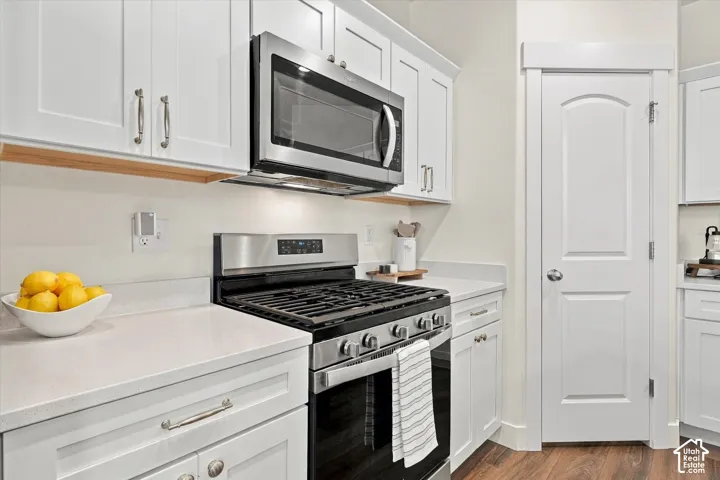 Shaker-style cabinetry, stainless steel gas range, over-the-range microwave, solid-surface countertops, and wood-finish flooring