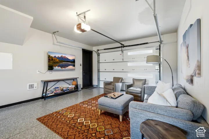 Attached garage featuring finished flooring, a motorized sectional garage door with horizontal light panels, and a dedicated entry door