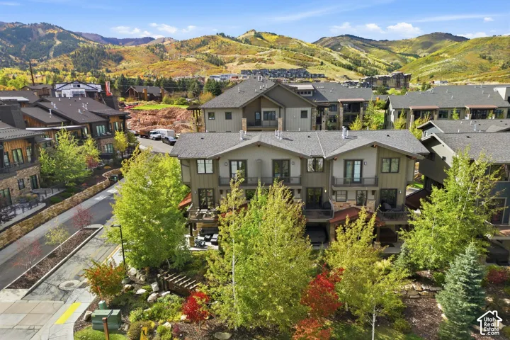 Multi-story exterior featuring stone and wood-composite siding, asphalt shingle roofing, private balconies with metal railings, and mountain backdrop