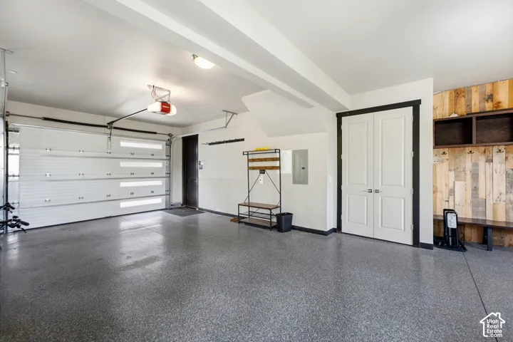 Attached two-car garage featuring a sectional door with frosted glass panel inserts, sealed speckled epoxy flooring, built-in wooden wall paneling, and double entry doors