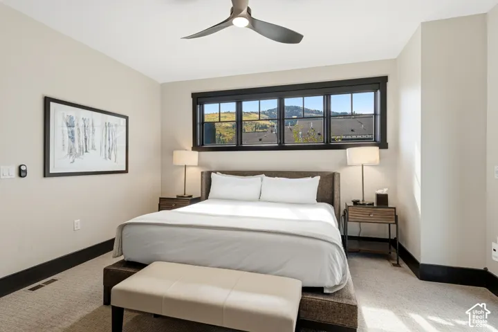 Horizontal window with dark casing, modern three-blade ceiling fan, and neutral carpeting
