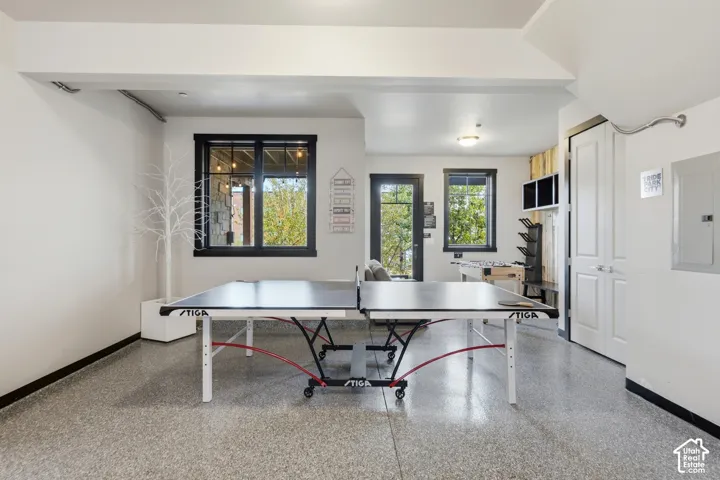 Finished interior space featuring speckled epoxy flooring, high-contrast black window trim, and a glass-paneled exterior door