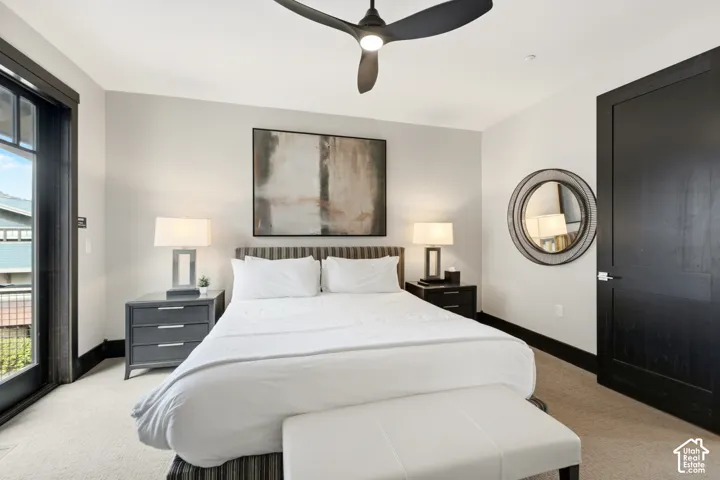 Spacious room featuring neutral carpeting, a dark-finish door with modern hardware, a ceiling fan with integrated lighting, and a glass-paneled door
