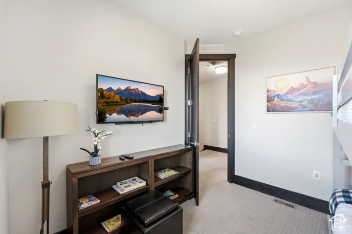 Room featuring neutral-toned carpeting, dark-stained door casing, and matching dark-stained wooden trim
