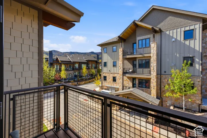 Private balcony with metal grid railings, stone veneer siding, shingle-patterned exterior cladding, vertical board siding, and mountain backdrop