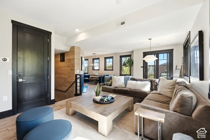 Open-concept living space featuring wood-finish flooring, high-contrast dark wood door and window trim, natural wood wall accents, recessed lighting, and glass-paned doors