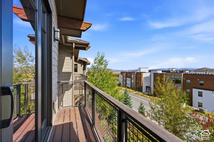 Private balcony featuring composite decking, a metal wire grid railing with a wooden top rail, and a mountain backdrop