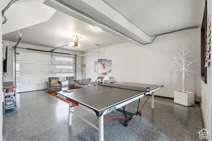 Finished garage space featuring durable epoxy-coated flooring, an overhead sectional garage door with horizontal window panes, and interior lighting