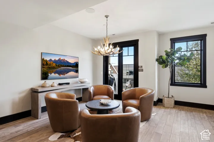 Living area featuring wood-finish flooring, high-contrast dark window and door trim, multi-pane glass door, and a decorative antler chandelier