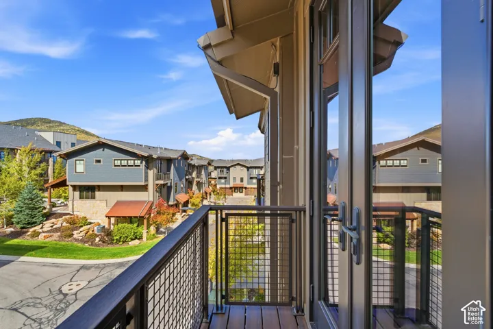 Exterior balcony with metal grid railing, composite decking, and dual-pane glass swing doors