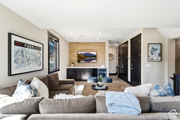 Wood-plank accent wall featuring built-in dark cabinetry, integrated wine refrigerator, recessed lighting, and wood-finish flooring