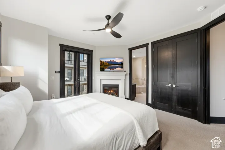 Gas fireplace with custom millwork surround, double French doors, dark-stained wood interior doors, and a modern three-blade ceiling fan