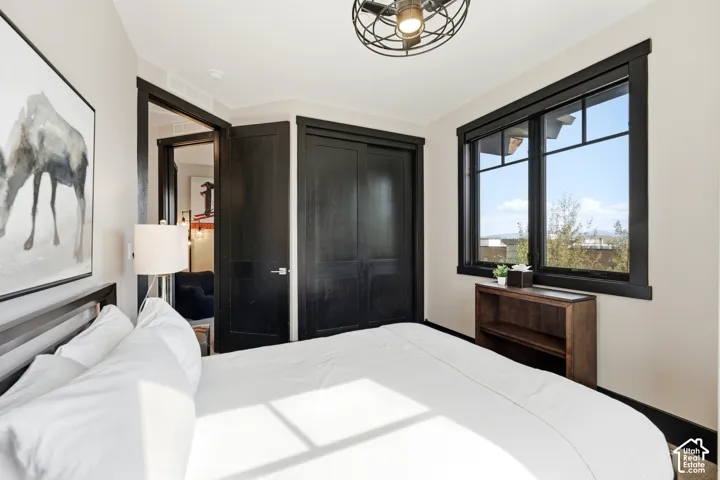 Bedroom featuring dark-finish trim, matching doors, a built-in closet with sliding panels, and a matte black industrial-style ceiling fixture