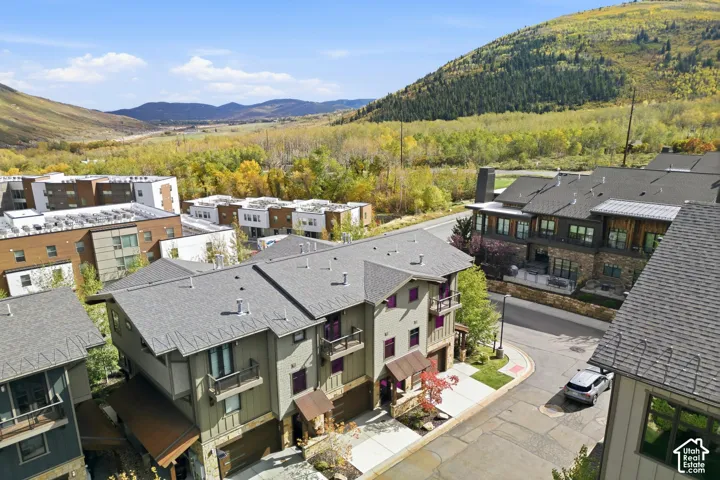 Multi-level residential structures featuring stone veneer siding, vertical board-and-batten siding, metal roof accents, and attached garages, set against a mountainous landscape