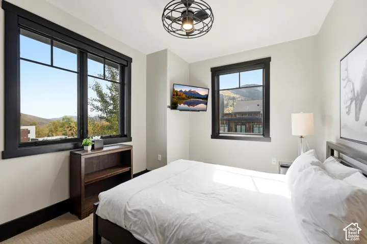 Neutral-toned interior featuring black-framed windows, built-in shelving, decorative cage-style ceiling lighting, and expansive mountain scenery