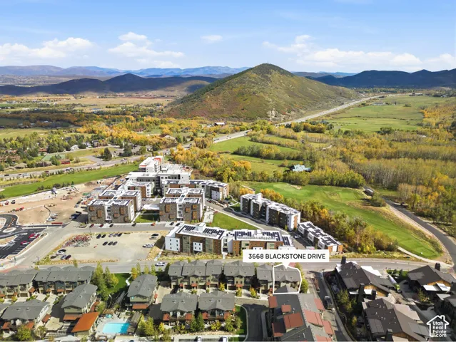 Aerial perspective of multi-story residential structures featuring rooftop solar panels, composite shingle roofing, and mountain range backdrop