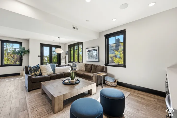 Living space featuring wood-finish flooring, recessed lighting, and expansive windows with black trim